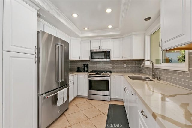 kitchen featuring stainless steel appliances, a tray ceiling, a sink, and white cabinets