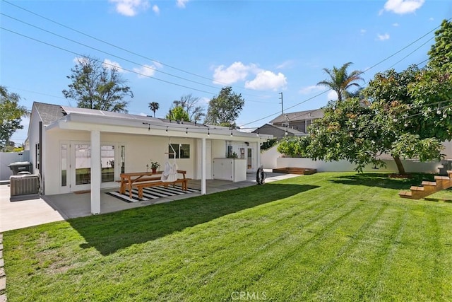 rear view of house with a patio area, a yard, fence, and stucco siding