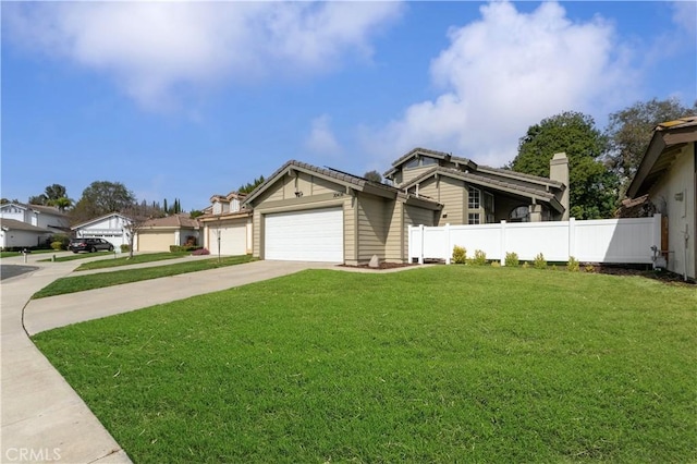 view of front of home with driveway, an attached garage, fence, and a front yard