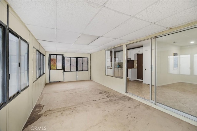 spare room with a paneled ceiling and concrete flooring