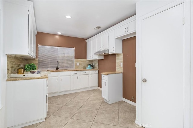 kitchen with white cabinets, light countertops, a sink, and visible vents