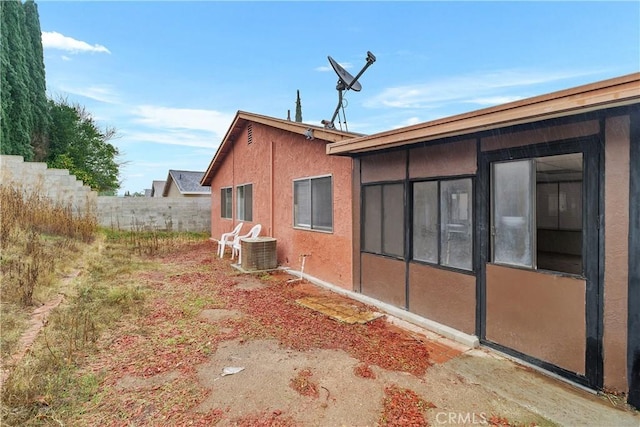 view of property exterior featuring central air condition unit, fence, and stucco siding