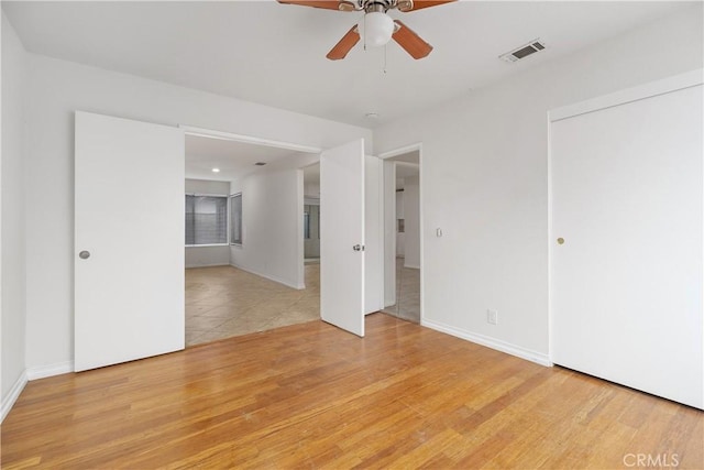 unfurnished room featuring baseboards, light wood finished floors, visible vents, and a ceiling fan