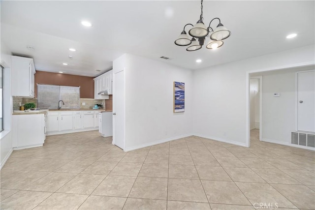 kitchen with light countertops, visible vents, decorative backsplash, light tile patterned flooring, and white cabinetry