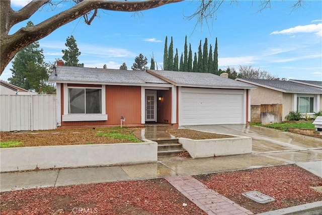 ranch-style home with concrete driveway, an attached garage, and fence