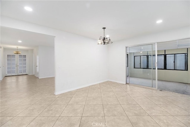 spare room with light tile patterned flooring, a notable chandelier, and baseboards