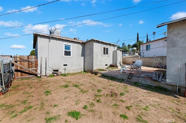 rear view of property with crawl space, a patio area, a fenced backyard, and stucco siding