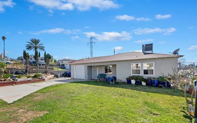 back of property featuring a garage, a yard, driveway, and stucco siding