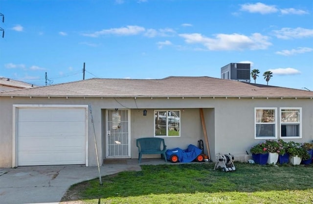 view of front of home with an attached garage, central AC, driveway, stucco siding, and a front lawn