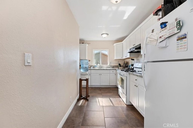 kitchen featuring white appliances, baseboards, white cabinets, under cabinet range hood, and a sink