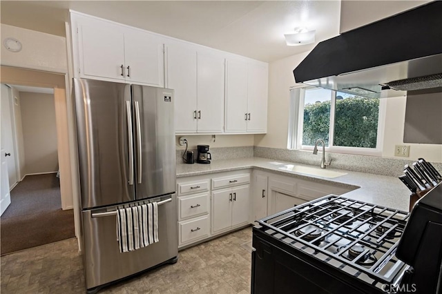 kitchen featuring a sink, extractor fan, white cabinetry, light countertops, and freestanding refrigerator
