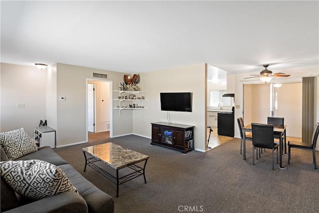 living room featuring dark carpet, visible vents, a ceiling fan, and baseboards