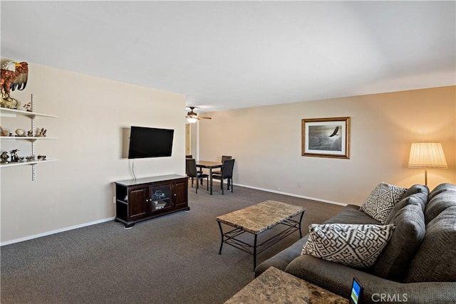 living area with a ceiling fan, dark carpet, and baseboards