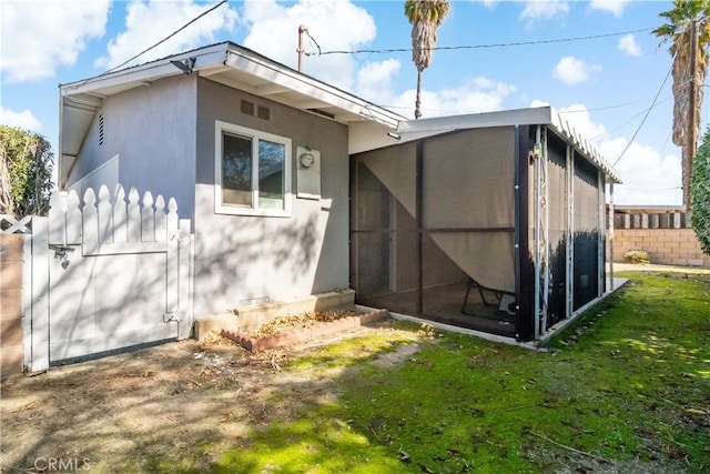back of property with stucco siding and a sunroom