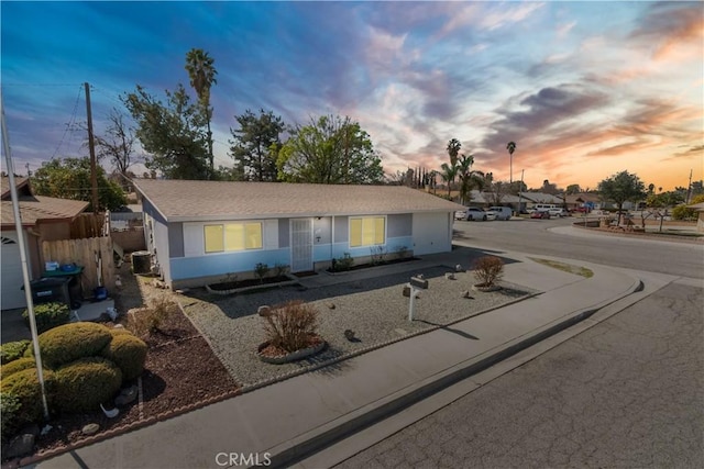 ranch-style home featuring central air condition unit, fence, and stucco siding