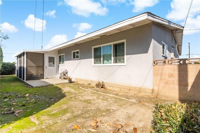 rear view of house with a sunroom and stucco siding