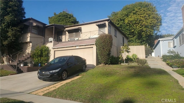 view of front of house featuring an attached garage, concrete driveway, stairway, stucco siding, and a front lawn