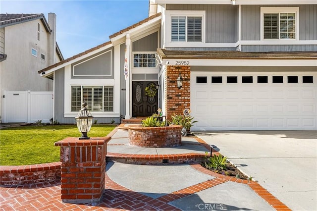 view of front of property featuring a garage, brick siding, fence, concrete driveway, and a front yard