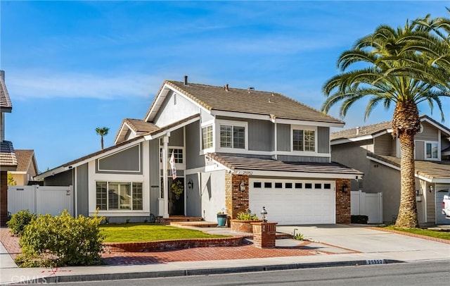 traditional-style home with driveway, a garage, fence, and brick siding