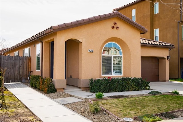 view of front facade featuring stucco siding, fence, a garage, driveway, and a tiled roof