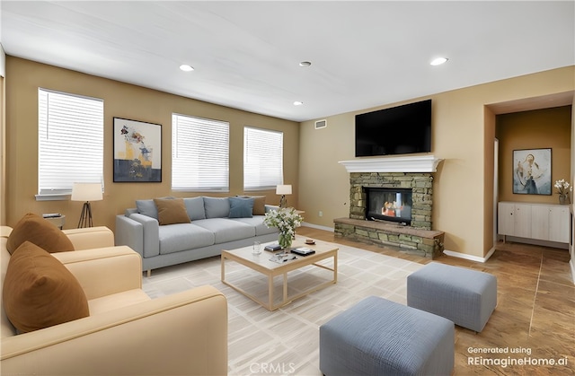 living room featuring recessed lighting, visible vents, a stone fireplace, and baseboards