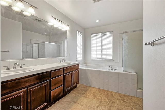 bathroom featuring a garden tub, double vanity, visible vents, a stall shower, and a sink