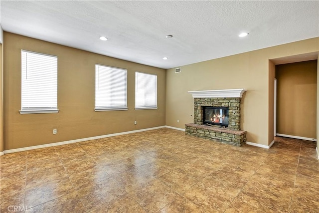 unfurnished living room with a textured ceiling, recessed lighting, a fireplace, visible vents, and baseboards