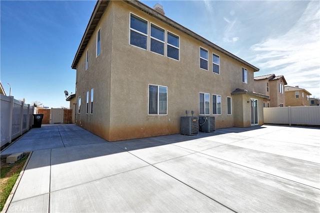 rear view of house featuring a patio area, fence, and stucco siding