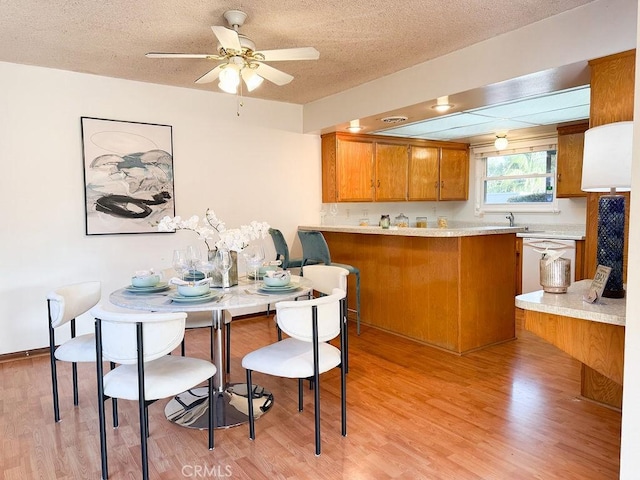 dining space with a textured ceiling, light wood finished floors, and a ceiling fan