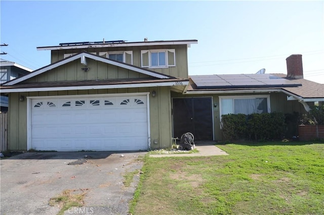 view of front of house with driveway, a garage, solar panels, a front lawn, and board and batten siding