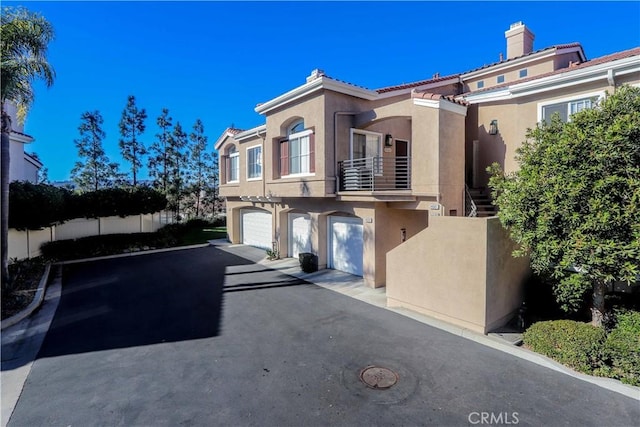 view of front of property featuring driveway, a balcony, an attached garage, and stucco siding