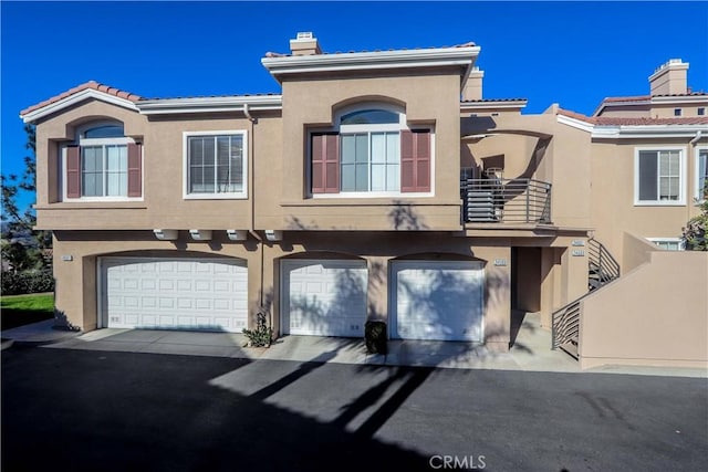 townhome / multi-family property with an attached garage, a chimney, and stucco siding