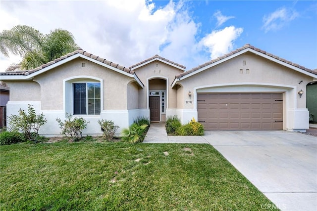 mediterranean / spanish house with a garage, concrete driveway, a tile roof, a front lawn, and stucco siding