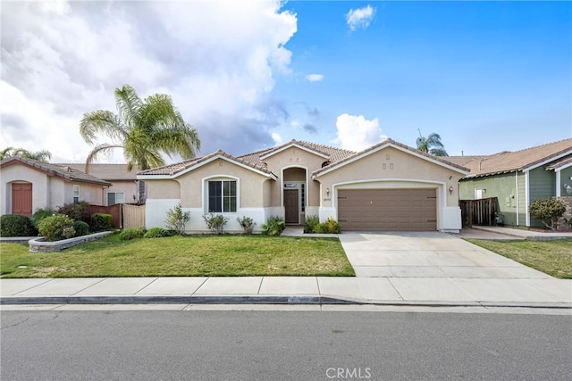 mediterranean / spanish-style home with a tile roof, stucco siding, concrete driveway, an attached garage, and a front lawn