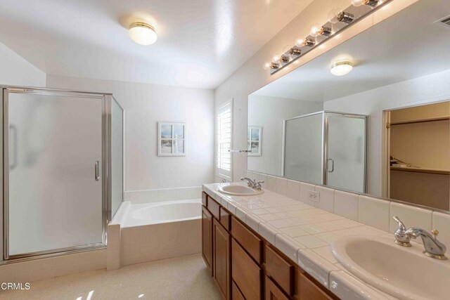 full bathroom featuring double vanity, a stall shower, a garden tub, and a sink