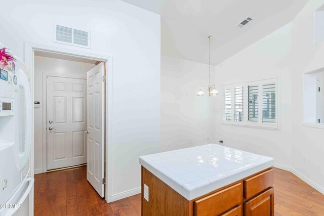 kitchen featuring tile counters, a center island, visible vents, and hanging light fixtures