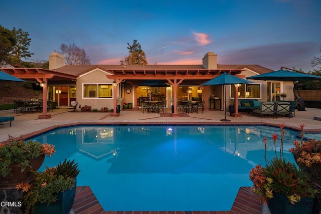 pool at dusk with a patio, an outdoor living space, and an outdoor pool