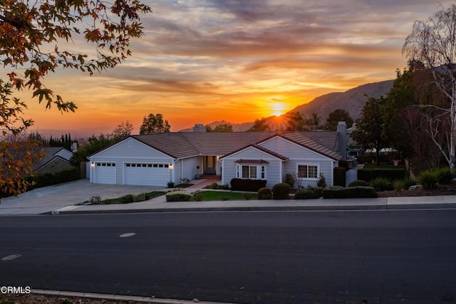 view of front of home featuring driveway, a tile roof, a garage, and a mountain view