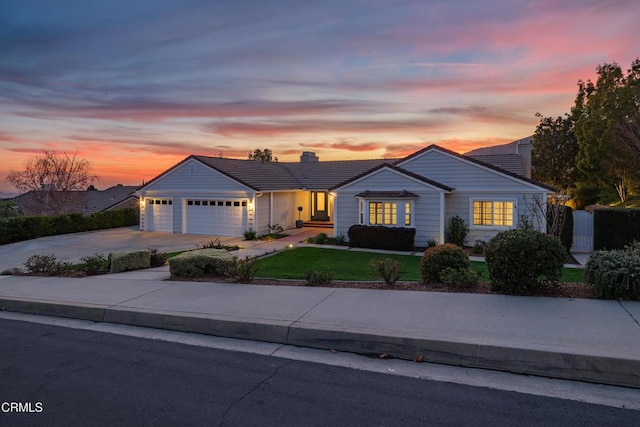 ranch-style house featuring concrete driveway, a tile roof, a lawn, and an attached garage