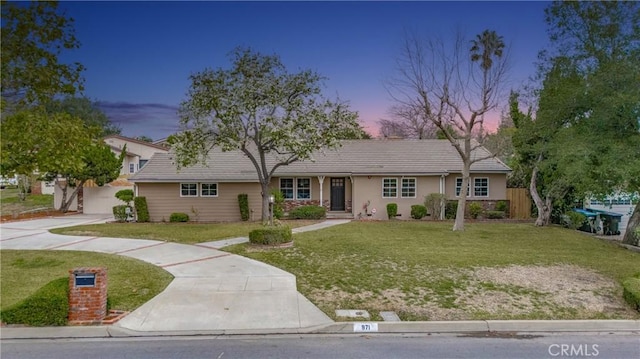 ranch-style home featuring concrete driveway and a yard