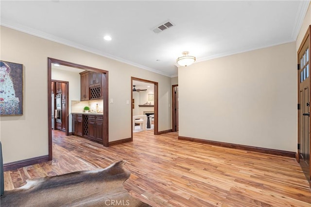 interior space featuring ornamental molding, light wood-style flooring, and baseboards