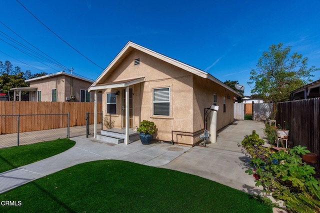 rear view of property with a patio, a lawn, fence private yard, and stucco siding