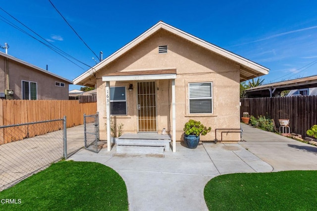 bungalow-style home featuring a patio area, fence, and stucco siding