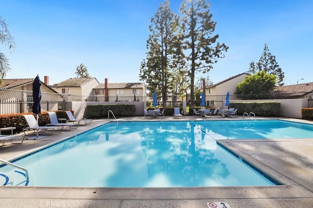 pool with a residential view, fence, and a patio