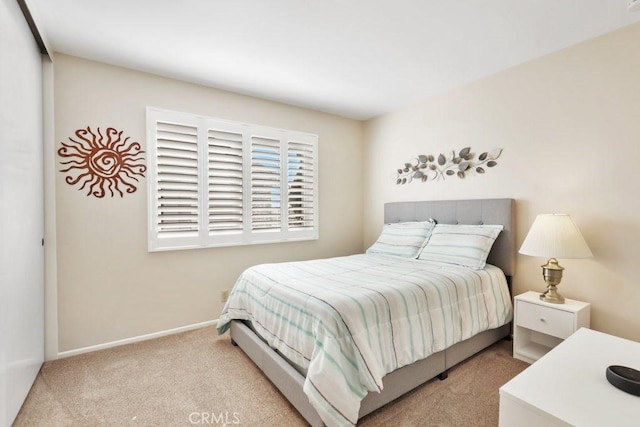 bedroom featuring light colored carpet and baseboards