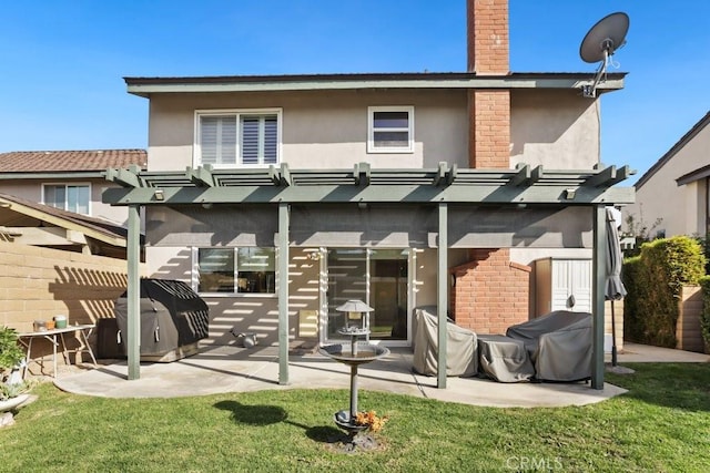 back of house with a chimney, stucco siding, a lawn, a patio area, and a pergola