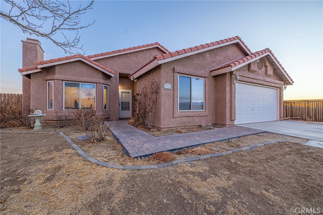 view of front of property featuring fence, a chimney, an attached garage, and stucco siding