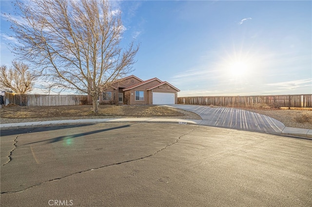 ranch-style home with an attached garage, fence, and concrete driveway