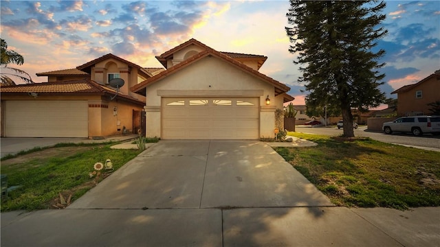 view of front of home with a yard, stucco siding, a garage, driveway, and a tiled roof