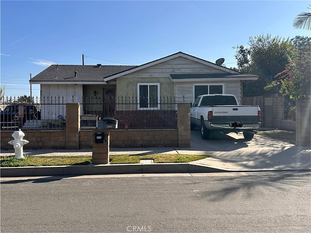 view of front of home featuring concrete driveway, a fenced front yard, and roof with shingles